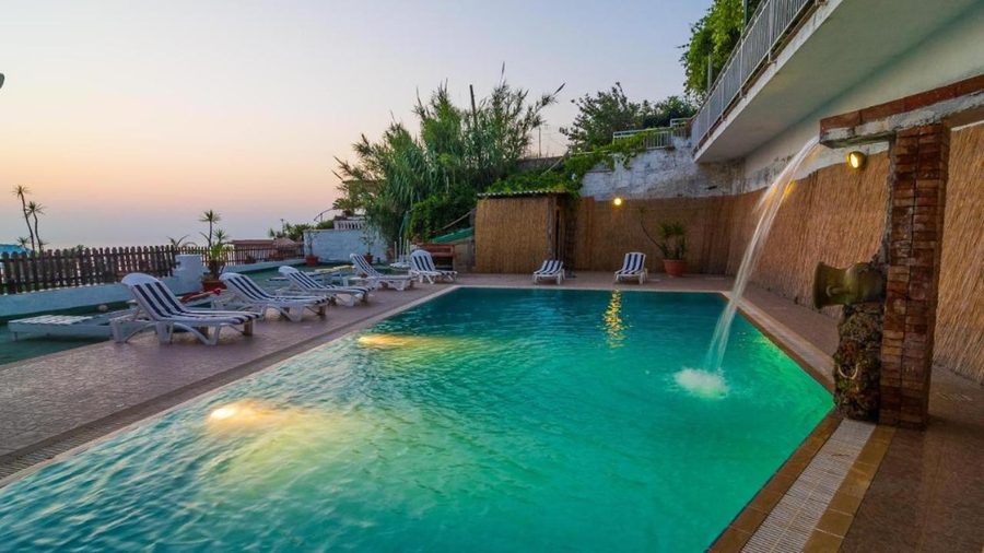 Piscina panoramica al crepuscolo con lettini e vista sul mare