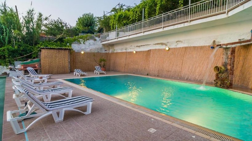 Piscina all'aperto con lettini e acqua turchese, immersa nel verde